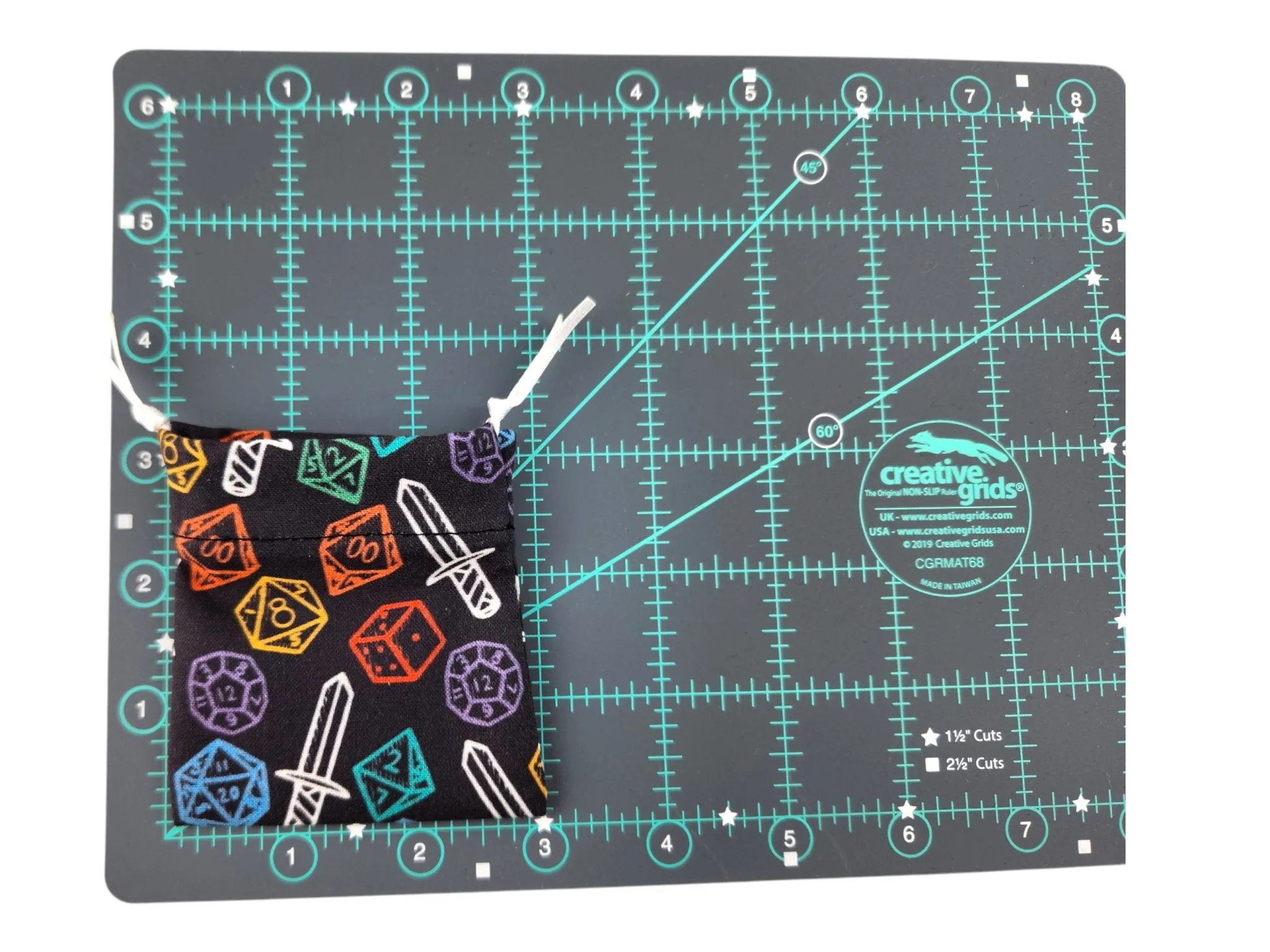 Mini drawstring bag with a set of mini dice, light teal with some glimmer.