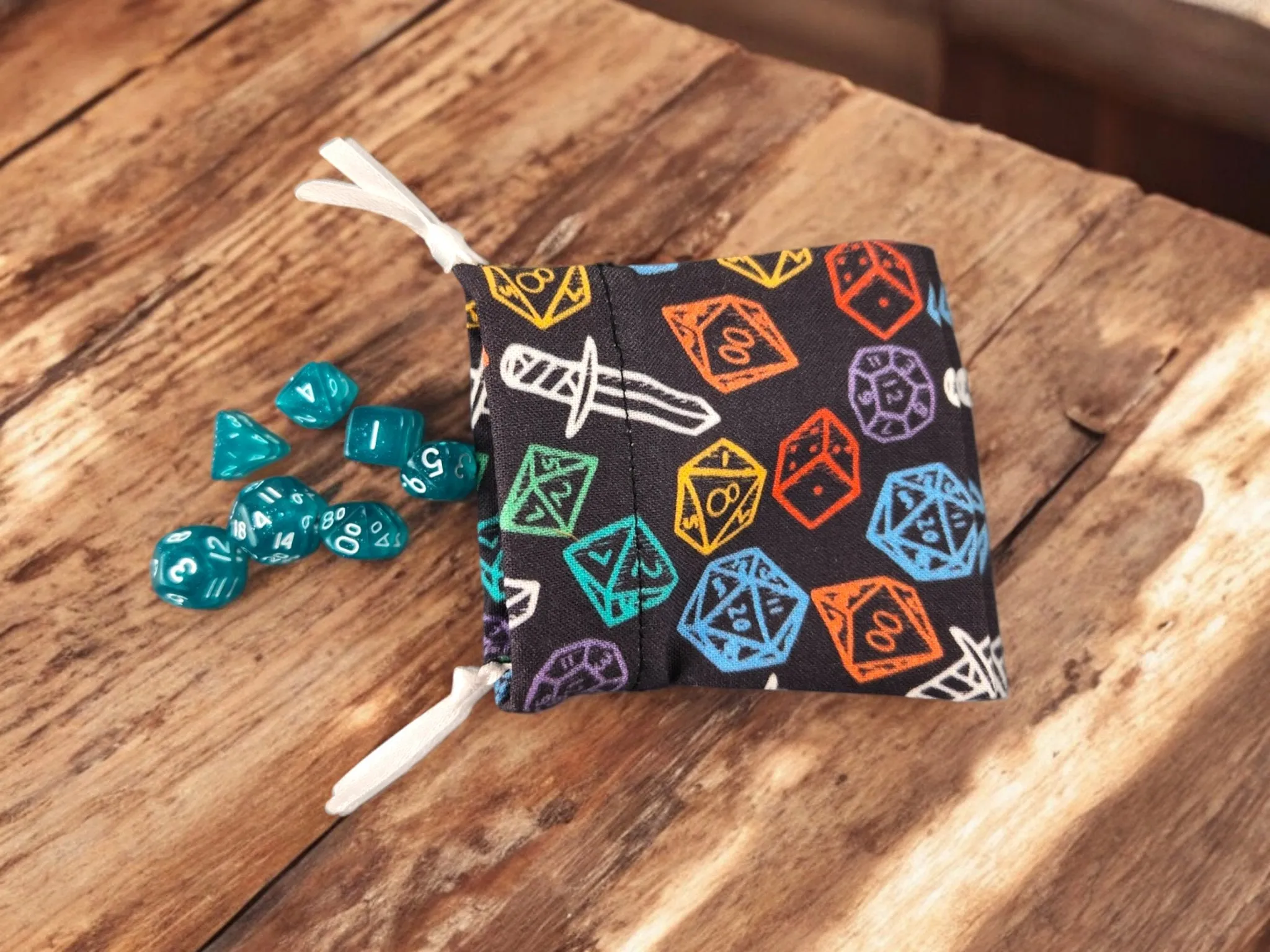 Mini drawstring bag with a set of mini dice, light teal with some glimmer.
